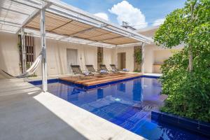 a swimming pool with chairs and a pergola at Nueva Apartasuite pleno centro in Santa Marta