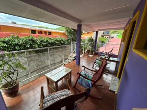 Un balcón con sillas y mesas. en Casa Romano Hostel, en San Juan del Sur