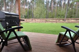 un grill e due sedie seduti su un ponte di Domek na Kaszubach 26-1 - Ostoja Bukowo a Borowy Młyn