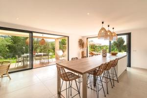 una cucina e una sala da pranzo con tavolo e sedie in legno di Bellezza - Villa climatisée piscine a Lecci