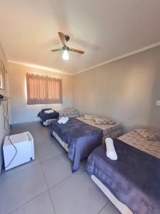 a bedroom with two beds and a ceiling fan at Recanto da lele in Aparecida