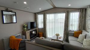 a living room with two couches and a tv at Sandy Feet Retreat, West Sands in Selsey