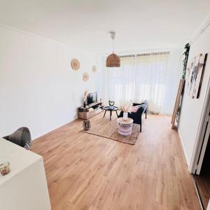 a living room with white walls and a wooden floor at zenitude in Marquette-lès-Lille +3 photos