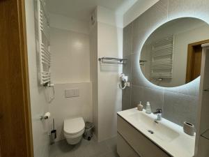 a bathroom with a sink and a toilet and a mirror at Caro - Naj Residence Dąbki in Dąbki +13 photos