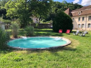 a pool in a yard with two chairs and a building at Abbaye de l'Etanche - 2 chambres d'hôtes - Un cadre naturel exceptionnel - in Rollainville