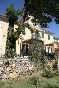 a house with a tree and a stone wall at Villa Fani in Rijeka