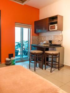 a kitchen with orange walls and a counter with stools at Suites Hamburgo in Mexico City
