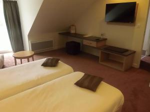 a hotel room with two beds and a flat screen tv at Hôtel Restaurant Le Rive Gauche in Joigny