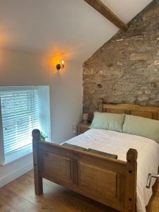ein Schlafzimmer mit einem Bett und einer Steinwand in der Unterkunft Cosy modern miners cottage in Llanllechid