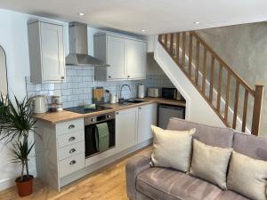 eine Küche mit weißen Schränken und einem Sofa im Wohnzimmer in der Unterkunft Cosy modern miners cottage in Llanllechid