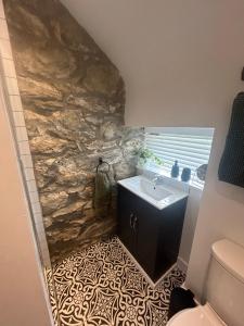 ein Badezimmer mit einem Waschbecken und einer Steinmauer in der Unterkunft Cosy modern miners cottage in Llanllechid + 19 Fotos