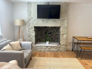 ein Wohnzimmer mit einem Steinkamin und einem Fernseher darauf in der Unterkunft Cosy modern miners cottage in Llanllechid