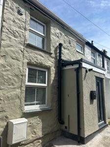 ein Backsteingebäude mit einer Tür und einem Fenster in der Unterkunft Cosy modern miners cottage in Llanllechid