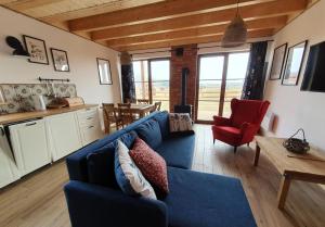 a living room with a blue couch and a kitchen at Domek na Kaszubach 34-1 - Ostoja Bukowo in Borowy Młyn