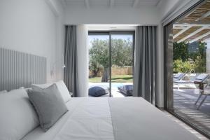 a bedroom with a large white bed and a patio at Astrum Luxury Suites in Vourvourou