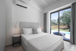 a white bedroom with a bed and a large window at Astrum Luxury Suites in Vourvourou