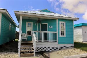 a blue tiny house with a porch and a chair at Shark Reef Resort Motel & Cottages in Port Aransas