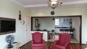 a living room with two pink chairs and a television at Apto 2Q Grande e Espaçoso in Curitiba