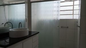 a bathroom with a sink and a glass shower at Apto 2Q Grande e Espaçoso in Curitiba