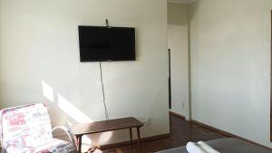 a living room with a tv on a white wall at Apto 2Q Grande e Espaçoso in Curitiba