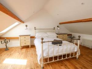 a bedroom with a white bed and a wooden floor at The Coach House in Cranwell
