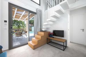 ein Wohnzimmer mit einer Treppe, einem TV und einem Tisch in der Unterkunft Astrum Luxury Suites in Vourvourou