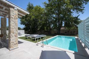 a swimming pool in a backyard with a table and chairs at Astrum Luxury Suites in Vourvourou
