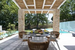 a patio with a table and chairs under a pergola at Astrum Luxury Suites in Vourvourou