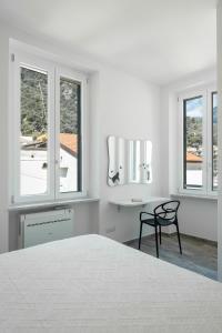 Un dormitorio blanco con una cama, un escritorio y ventanas. en Il gatto Franco, en Amalfi