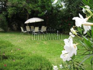 a group of chairs and an umbrella in a yard at Très Bel Appartement familial sur Rabat Temara PLAGES avec Piscines in El Harhoura