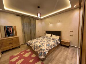 a bedroom with a bed and a dresser and a mirror at Très Bel Appartement familial sur Rabat Temara PLAGES avec Piscines in El Harhoura +5 photos