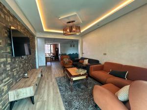 a living room with a couch and a tv at Très Bel Appartement familial sur Rabat Temara PLAGES avec Piscines in El Harhoura