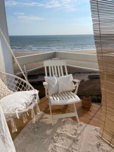una sedia a dondolo bianca su un balcone con vista sull'oceano di Bohème vue mer a Saint-Gilles-Croix-de-Vie