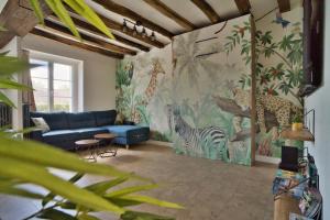 Una sala de estar con un sofá azul y animales pintados en la pared. en Le Toucan, en Saint-Aignan