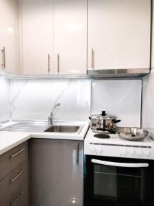 a white kitchen with a sink and a stove at Classy Louvis House in Akti Salonikiou