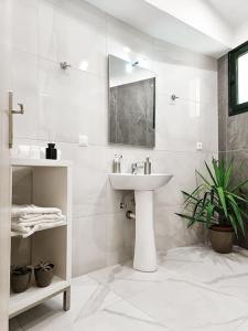 a white bathroom with a sink and a mirror at Classy Louvis House in Akti Salonikiou