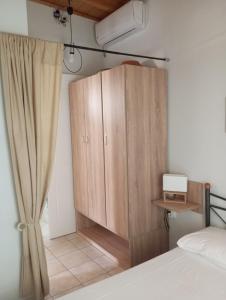 1 dormitorio con armario de madera junto a la cama en Lefakis cottage, en Órmos