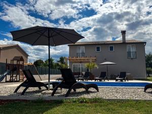 patio z krzesłami, parasolem i placem zabaw w obiekcie Villa Anastazija w mieście Labin