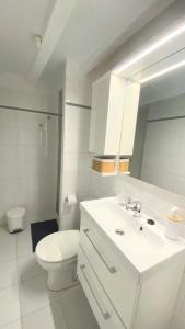 a white bathroom with a toilet and a sink at Sol y Mar Villajoyosa in Villajoyosa