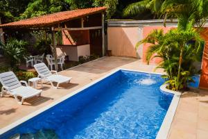 a swimming pool with two chairs and a house at Morena Jambo in Arraial d'Ajuda