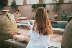 een vrouw zit op een richel en houdt een mobiele telefoon vast bij Relais Conac 1888 - Luxury B&B - Adults Only in Castelnuovo Don Bosco