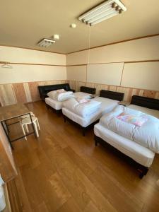 a row of beds in a room with wood floors at Tengudaira Mountain Lodge in Tateyama