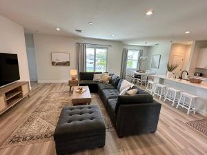 a living room with a black couch and a kitchen at Cape Coral-Ft Myers Waterfront Four Bedroom Home in Cape Coral