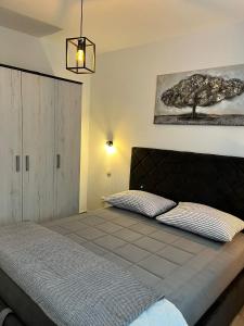 a bedroom with a bed and a tree on the wall at Apartment Potocnica 222a in Novalja
