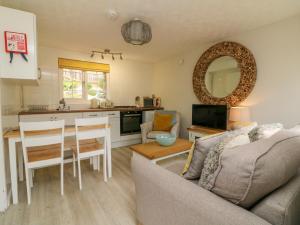 eine Küche und ein Wohnzimmer mit Sofa und Tisch in der Unterkunft Swallow Cottage in Ilfracombe