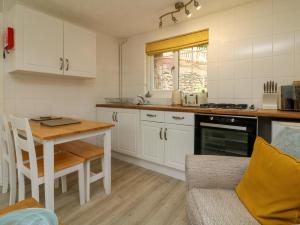 eine Küche mit weißen Schränken, einem Tisch und einem Esszimmer in der Unterkunft Swallow Cottage in Ilfracombe + 12 Fotos