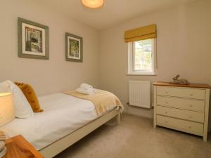 ein Schlafzimmer mit einem Bett, einer Kommode und einem Fenster in der Unterkunft Swallow Cottage in Ilfracombe