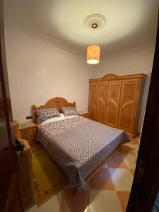 une chambre avec un lit et une armoire en bois dans l'établissement Martil résidence, à Martil 1 autre photo