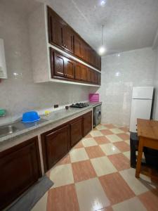 - une cuisine avec des placards en bois et un sol en damier dans l'établissement Martil résidence, à Martil