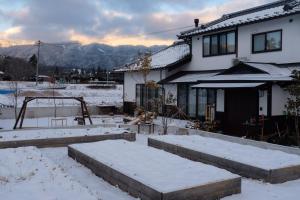 a yard covered in snow with a house at 安曇野ふくろうハウス The OWL Villa mountain view in Hotaka